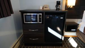 a black cabinet with a microwave and a television at Budget Host Inn Fridley in Fridley