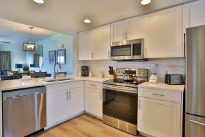 eine Küche mit weißen Schränken und Küchengeräten aus Edelstahl in der Unterkunft 611-N - Sunset Vistas in St Pete Beach