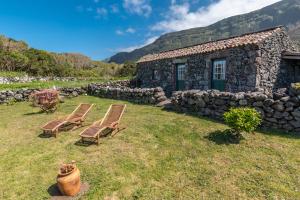 two chairs in front of a stone house at Aldeia da Cuada in Faja Grande