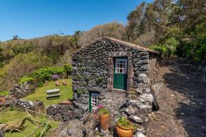 a small stone house with a green door and a bench at Aldeia da Cuada in Faja Grande
