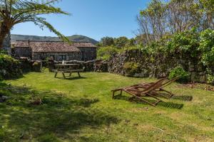 a yard with two picnic tables and a building at Aldeia da Cuada in Faja Grande