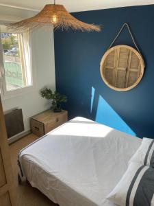 1 dormitorio con cama y pared azul en Le P'tit Carnon en Mauguio