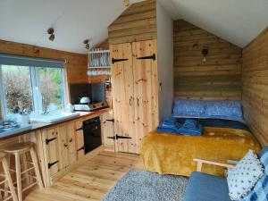 a small bedroom with a bed and a kitchen at Dryw bach glamping hut in Llandeilo