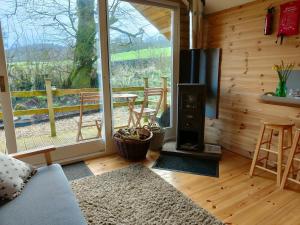 a living room with a fireplace and a large window at Dryw bach glamping hut in Llandeilo