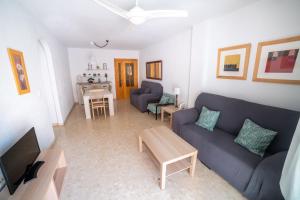 sala de estar con sofá azul y mesa en Apartamento con piscina y terraza a 50 metros de la playa, en Roquetas de Mar