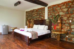 a bedroom with a bed in a stone wall at Vertikal lodge in Santa Teresa