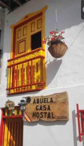a sign on the side of a building with a flower pot at Abuela Casa Hostal in Apía