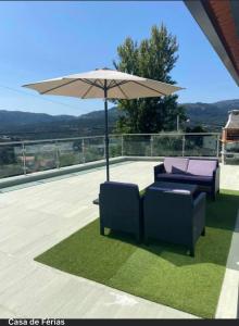 un patio con 2 sillas y una sombrilla en Terraço d’Aldeia, en São Pedro do Sul