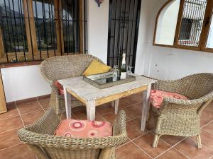 a table with wicker chairs and a bottle of wine at Belvilla by OYO Villa Antonio Alto 4 pax in Benichembla