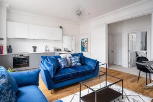River Street View في باث: غرفة معيشة مع أريكة زرقاء ومطبخ