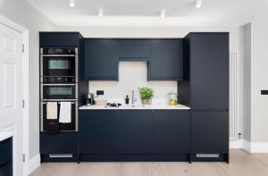 uma cozinha com armários azul marinho e um lavatório em Wine Vaults Apartment em Bath