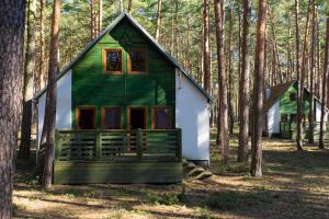 uma pequena casa verde e branca na floresta em Sława Family Resort em Lubiatów