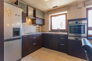 a kitchen with brown cabinets and a sink and a refrigerator at Apartament w Sercu Miasta in Elblag