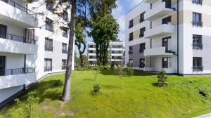 um edifício de apartamentos com um pátio verde em frente em SandLand - Rezydencja Ustronie Morskie - Apartamenty em Ustronie Morskie