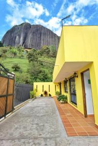a yellow house with a mountain in the background at Hermosa casa de campo en GUATAPÉ in Guatapé