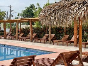 - un groupe de chaises et une piscine avec un parasol dans l'établissement La Mansión del Faro, à Tecolutla