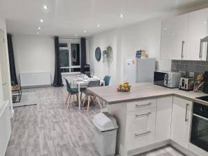 a kitchen with white cabinets and a table with chairs at 6 Bed sleeps 7, 1 mile from M54 i54 Jaguar Land Rover MOOG in Wolverhampton