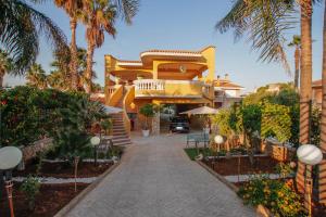 a yellow house with palm trees and a driveway at Villa Silvana-Fronte Mare in Marsala