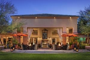 a home with a patio with chairs and umbrellas at Sonesta Suites Scottsdale Gainey Ranch in Scottsdale