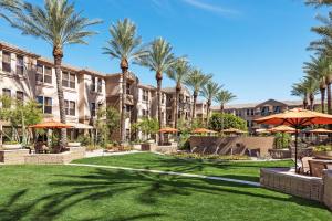 a courtyard at the resort with palm trees and umbrellas at Sonesta Suites Scottsdale Gainey Ranch in Scottsdale