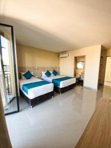 two beds in a large room with a mirror at Balcones de la Quinta in Ríohacha