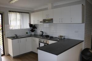 a kitchen with white cabinets and a black counter top at Western Sydney University Village - Hawkesbury in Richmond