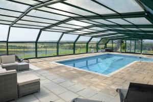 een zwembadhuis met een glazen dak en een zwembad bij Tregaddra Farm B&B in Helston