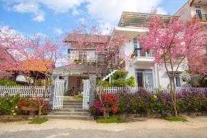 a white house with flowering trees in front of it at Đỗ Gia Bảo Villa in Da Lat