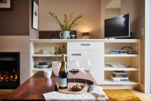 a room with a table with wine glasses and a fireplace at Parehua Resort in Martinborough 