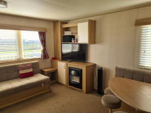 a living room with a couch and a tv and a table at 8 Berth The Chase Ingoldmells (Horizon) in Ingoldmells