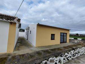 a small yellow and white building next to a wall at Riviera Beach AL in Praia da Vitória