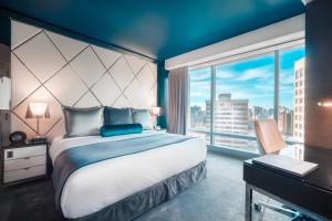 a bedroom with a large bed and a large window at Paradox Hotel Vancouver in Vancouver