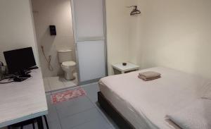 a small bedroom with a bed and a toilet at Fifty Seven Inn in Batu Pahat