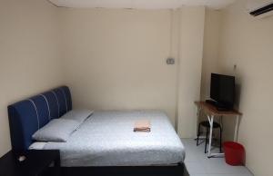 a small bedroom with a bed and a television at Fifty Seven Inn in Batu Pahat