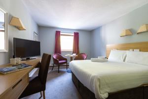 una camera d'albergo con letto, scrivania e TV di The Caledonian Hotel a Fort William