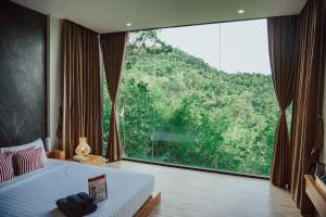 a bedroom with a bed and a large window at Veravian Resort in Wang Nam Khieo