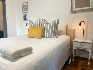 1 dormitorio con cama blanca y almohadas a rayas en Blue Duck Cottage Village Comfort with Fireplace en Tenterfield