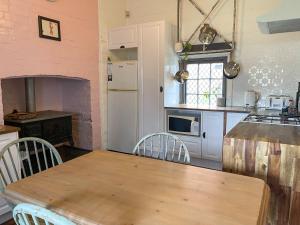 a kitchen with a wooden table and a kitchen with a stove at Blue Duck Cottage Village Comfort with Fireplace in Tenterfield