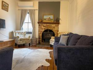 een woonkamer met een bank en een open haard bij Blue Duck Cottage Village Comfort with Fireplace in Tenterfield