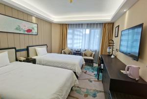 広州市にあるGuangdong Hotel-Free Shuttle & Registration Counter Service during Canton Fairのベッド2台と薄型テレビ付きのホテルの部屋