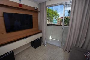 a living room with a flat screen tv and a window at Colecione histórias Guarapari, localização Top!!! in Guarapari