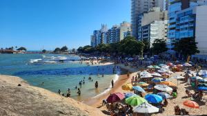 a group of people on a beach with umbrellas at Colecione histórias Guarapari, localização Top!!! in Guarapari