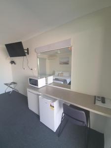 Habitación con escritorio, cama y espejo. en Sun City Motel en Bundaberg
