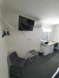 Habitación con silla y TV en la pared. en Sun City Motel en Bundaberg