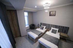Una habitación de hotel con dos camas y una ventana. en Samarqand Darvoza, en Bukhara