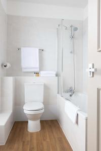 a white bathroom with a toilet and a bath tub at The St Ives Bay Hotel in St Ives