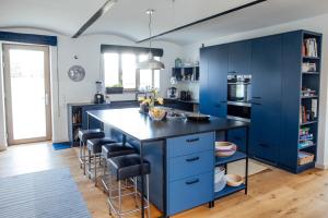 eine blaue Küche mit einer großen Insel mit Barhockern in der Unterkunft OLLERS in Ollersdorf im Burgenland