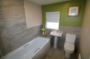 a bathroom with a tub and a toilet and a sink at Beulah Guest House in Portrush