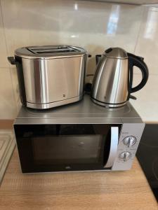 a slow cooker and a pot on top of a microwave at Central Cosy Apartment in Cologne in Cologne