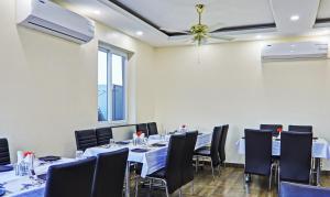 Habitación con mesas, sillas y ventilador de techo. en Treebo Trend Raj Inn Lalpur, en Ranchi